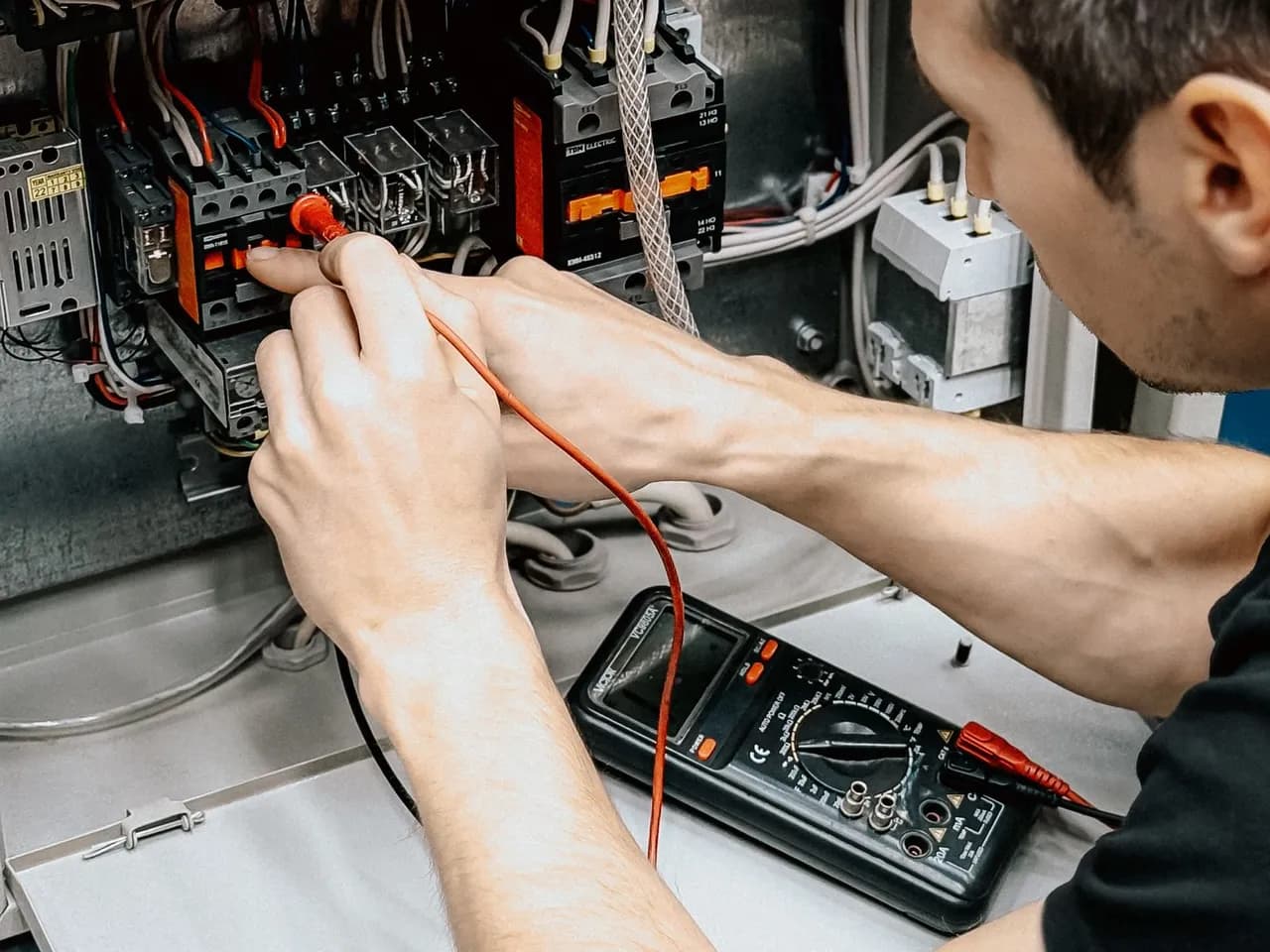 Électricien contrôlant les connexions d’un tableau électrique avec un multimètre