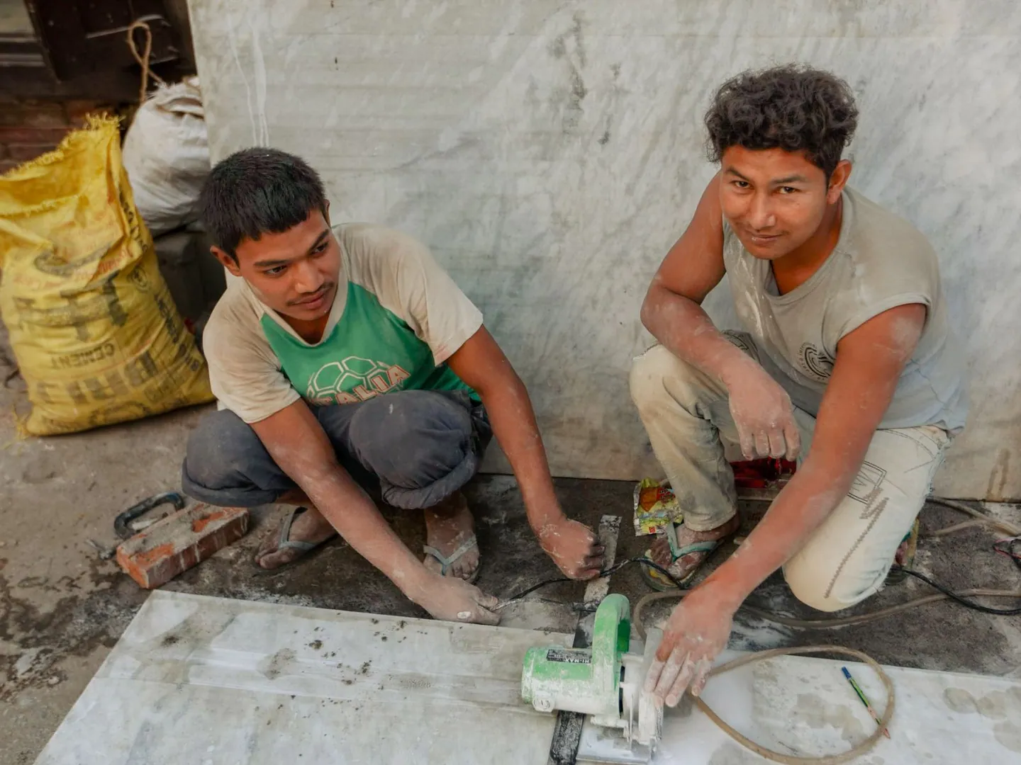 Deux artisans utilisant un outil de découpe sur un chantier de pose de revêtement de sol