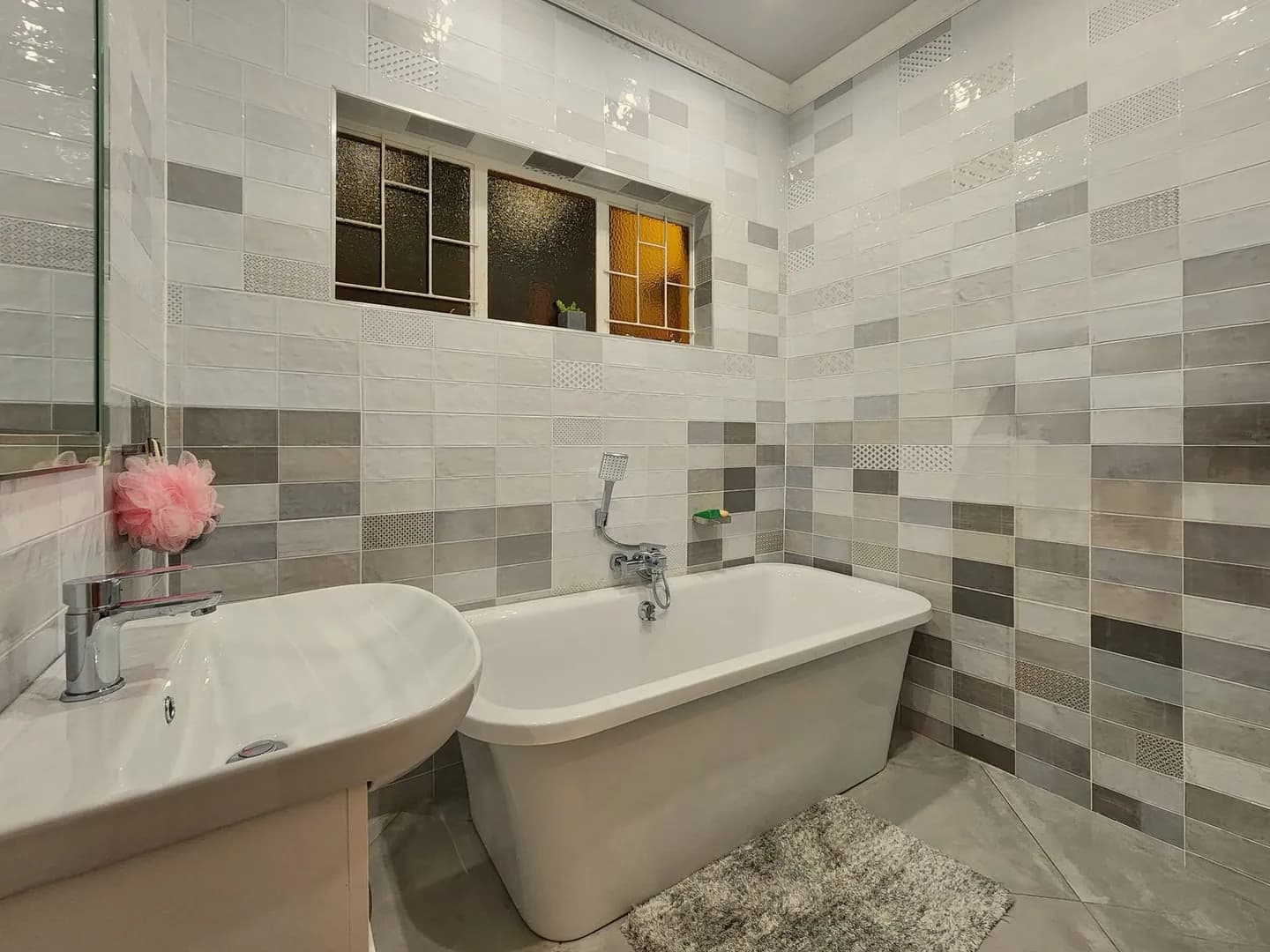 Salle de bain contemporaine avec carrelage clair, baignoire et équipements sanitaires