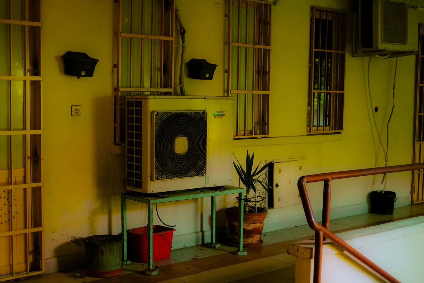 Groupe extérieur de climatisation installé sur un balcon avec des plantes en pot