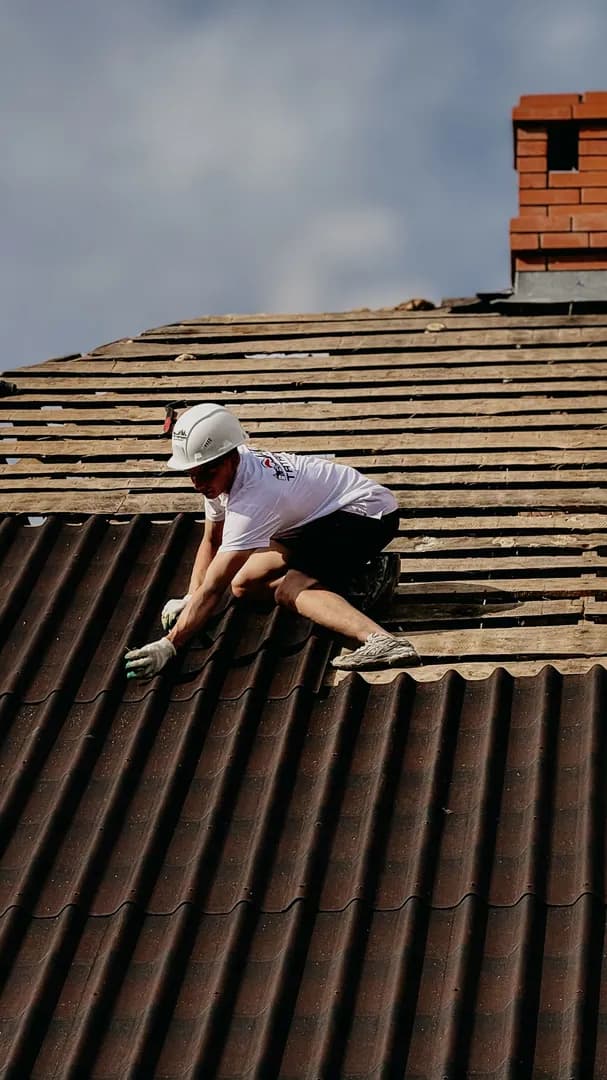 Couvreur portant des équipements de protection sur une toiture inclinée en tuiles