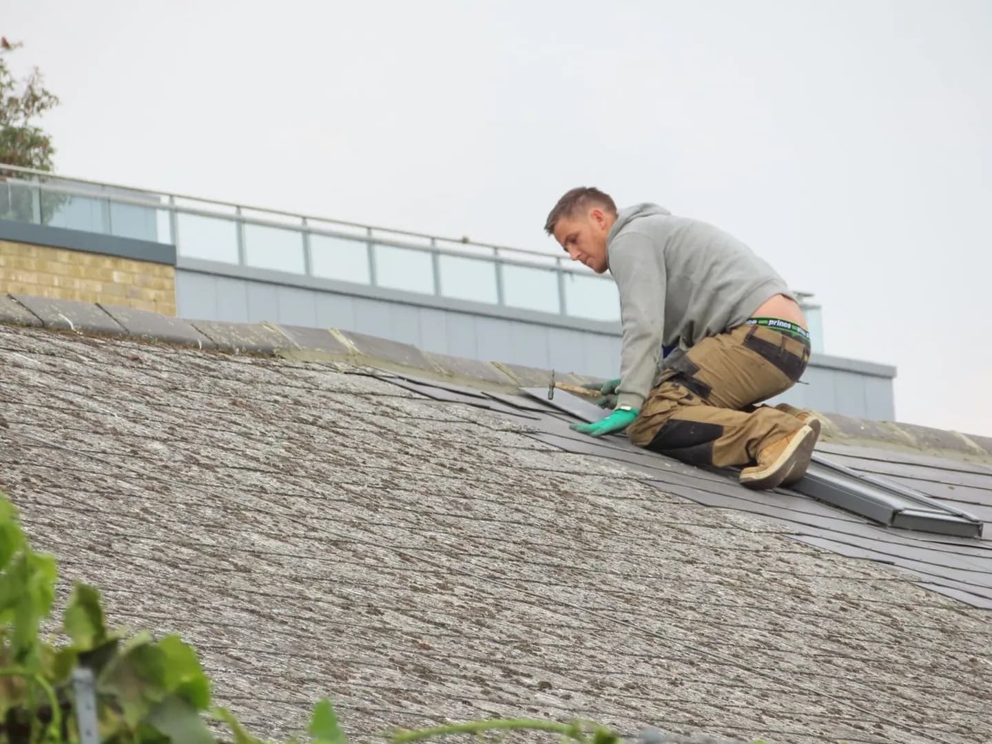 Artisan travaillant à la pose de bardeaux sur la toiture d’une maison