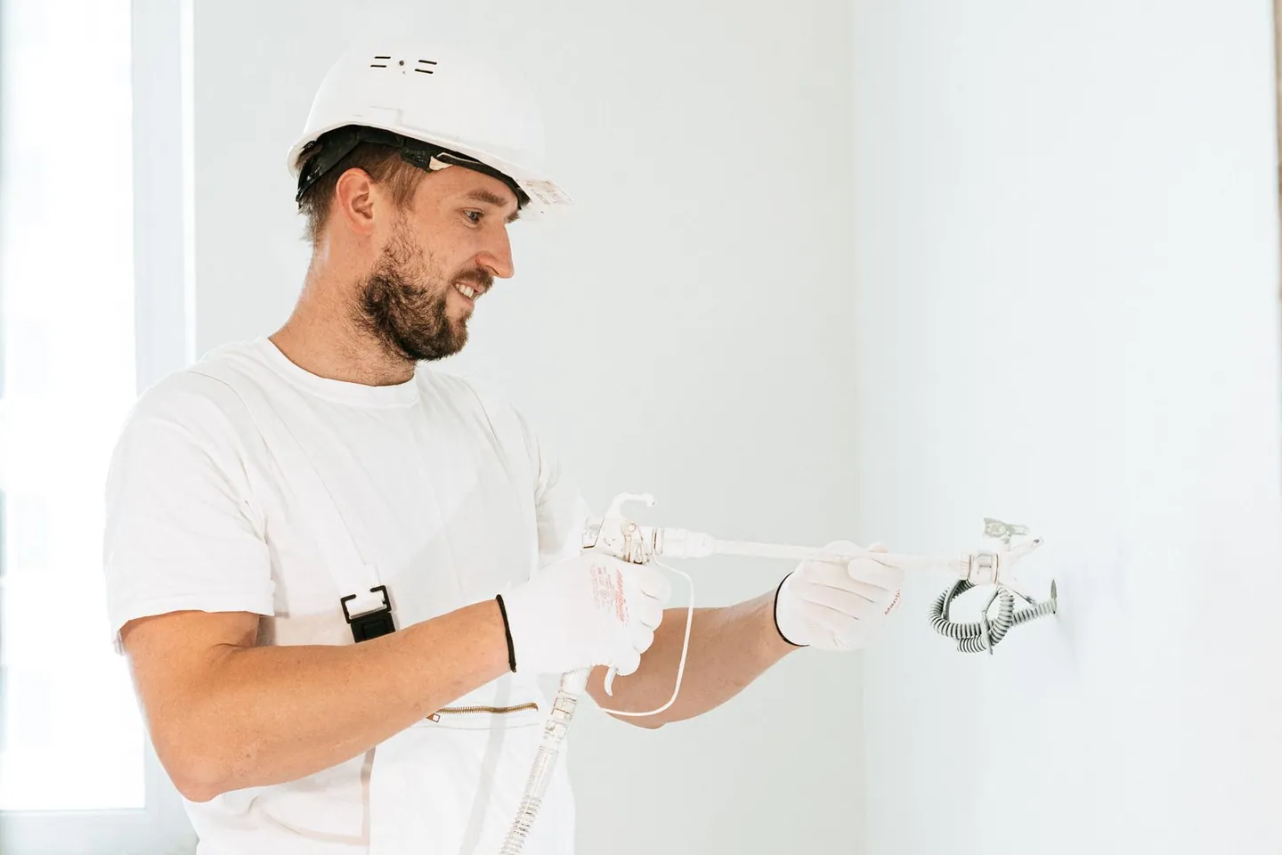 Électricien avec un casque de protection intervenant sur le câblage mural d’un bâtiment