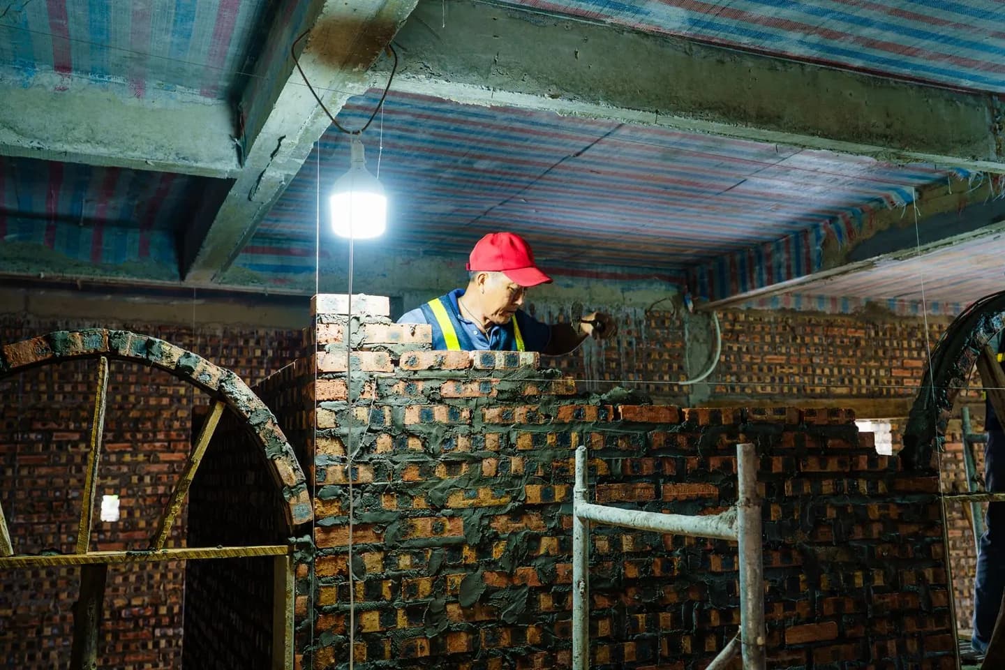 Ouvrier construisant un mur en briques à l’intérieur d’un chantier de bâtiment