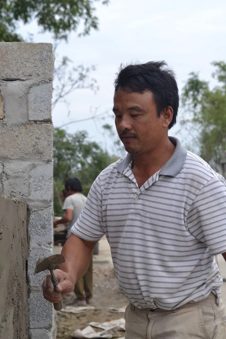 Maçon appliquant du mortier à la truelle sur un mur en cours de construction