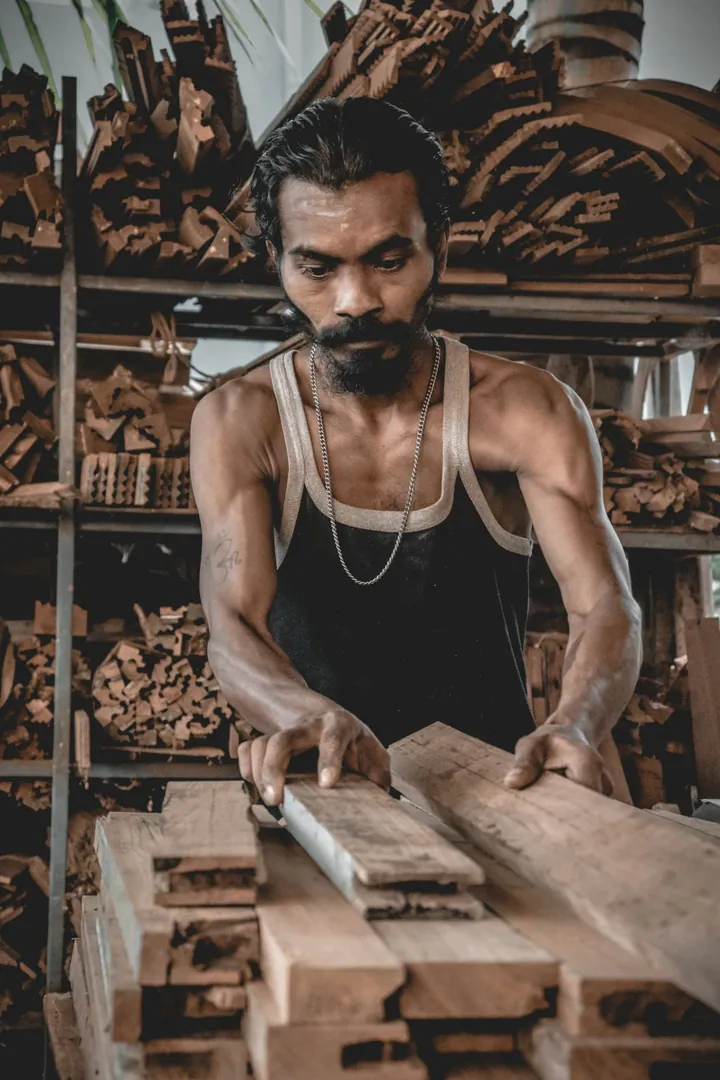 Artisan travaillant le bois dans un atelier entouré de planches et de machines