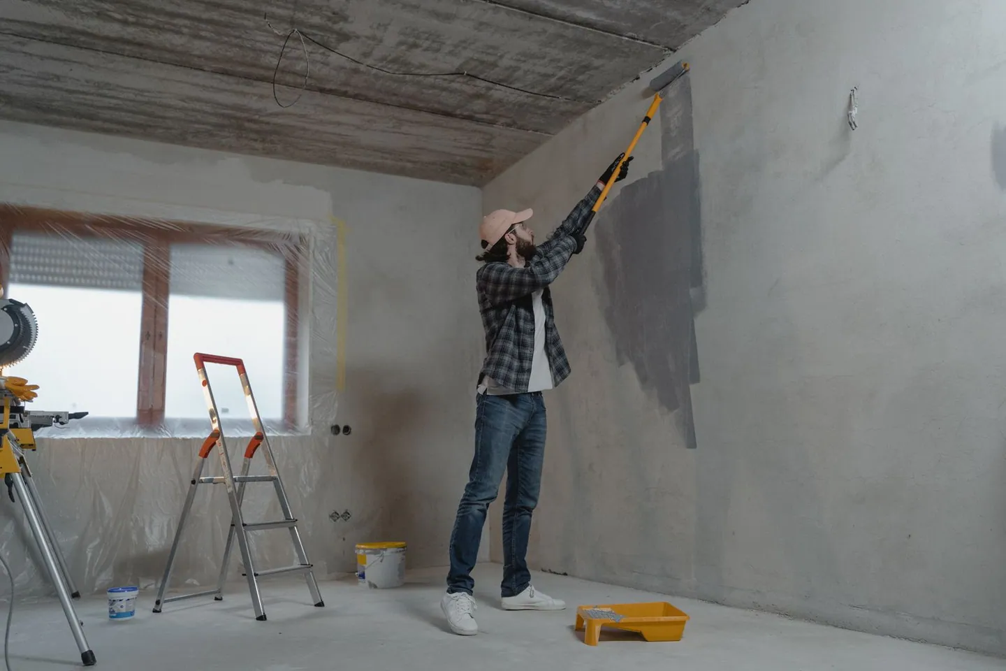 Peintre appliquant de la peinture au rouleau sur un mur pendant une rénovation intérieure