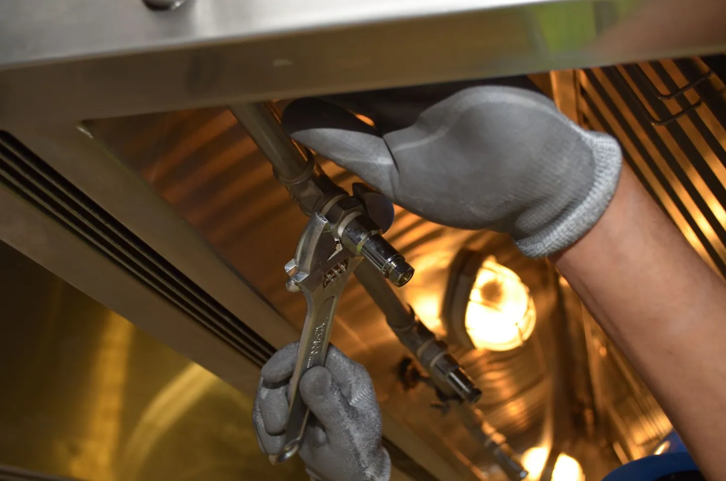 Mains gantées utilisant une clé sur des raccords de tuyauterie dans un local technique