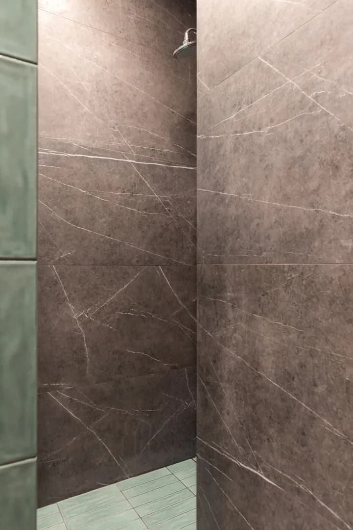 Espace douche équipé de robinetterie, avec parois en marbre et carrelage vert
