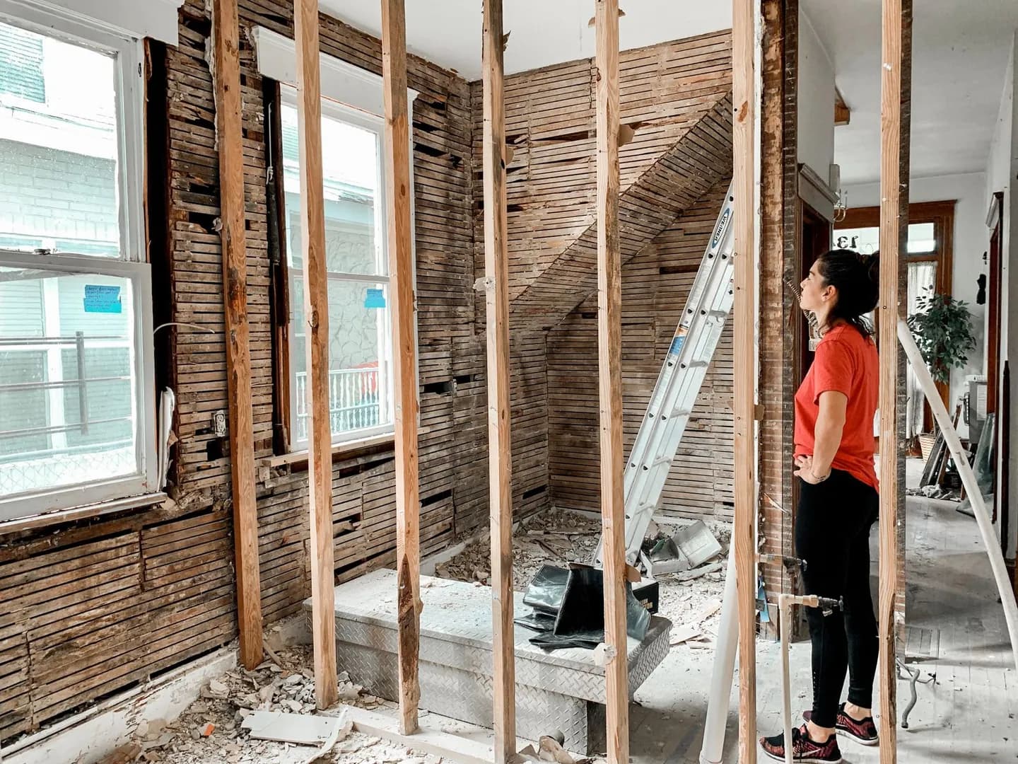 Personne observant une pièce en travaux avec des parois ouvertes et une structure en bois visible