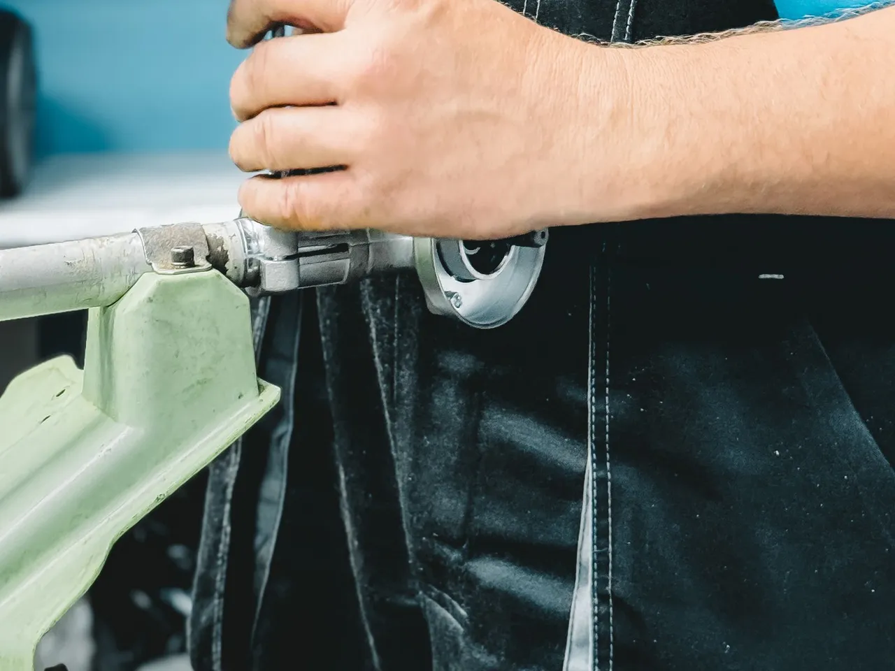 Plombier en tenue bleue serrant un raccord de tuyauterie avec une clé