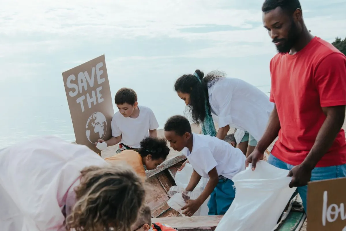 Un groupe d’adultes et d’enfants ramasse les déchets sur une plage avec des sacs de collecte