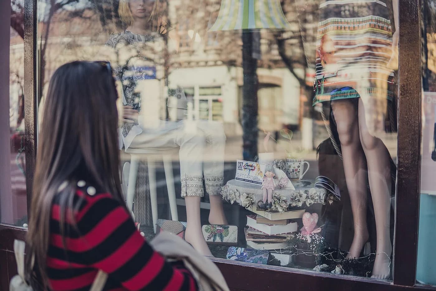 Une passante regarde une vitrine de boutique