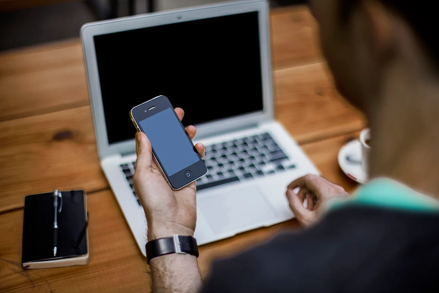 Une personne utilise un smartphone devant un ordinateur portable