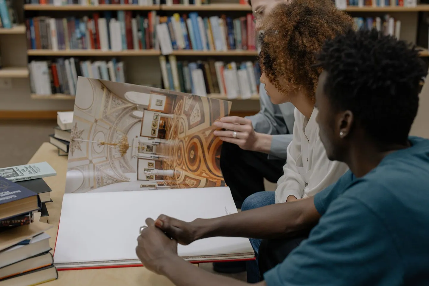 Adultes réunis autour d’un livre ouvert dans une bibliothèque