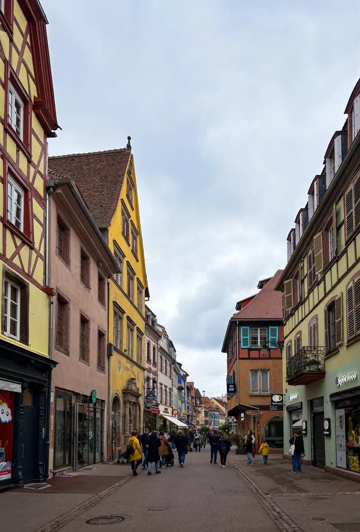 Passants dans une rue de village français bordée de maisons à colombages