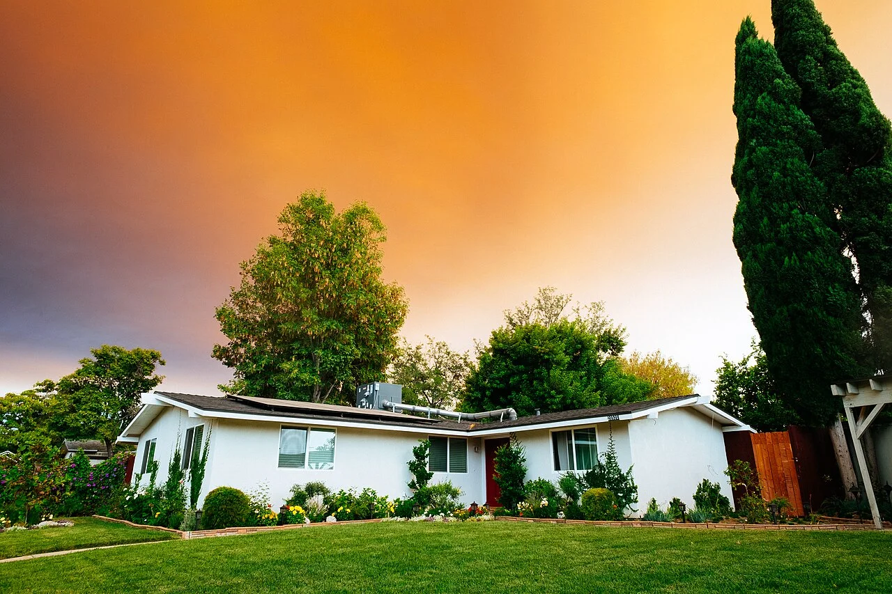 Maison blanche de plain-pied entourée d’un jardin arboré