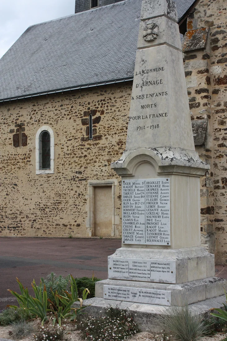 Le monument aux morts au premier plan devant l’église d’Arnage