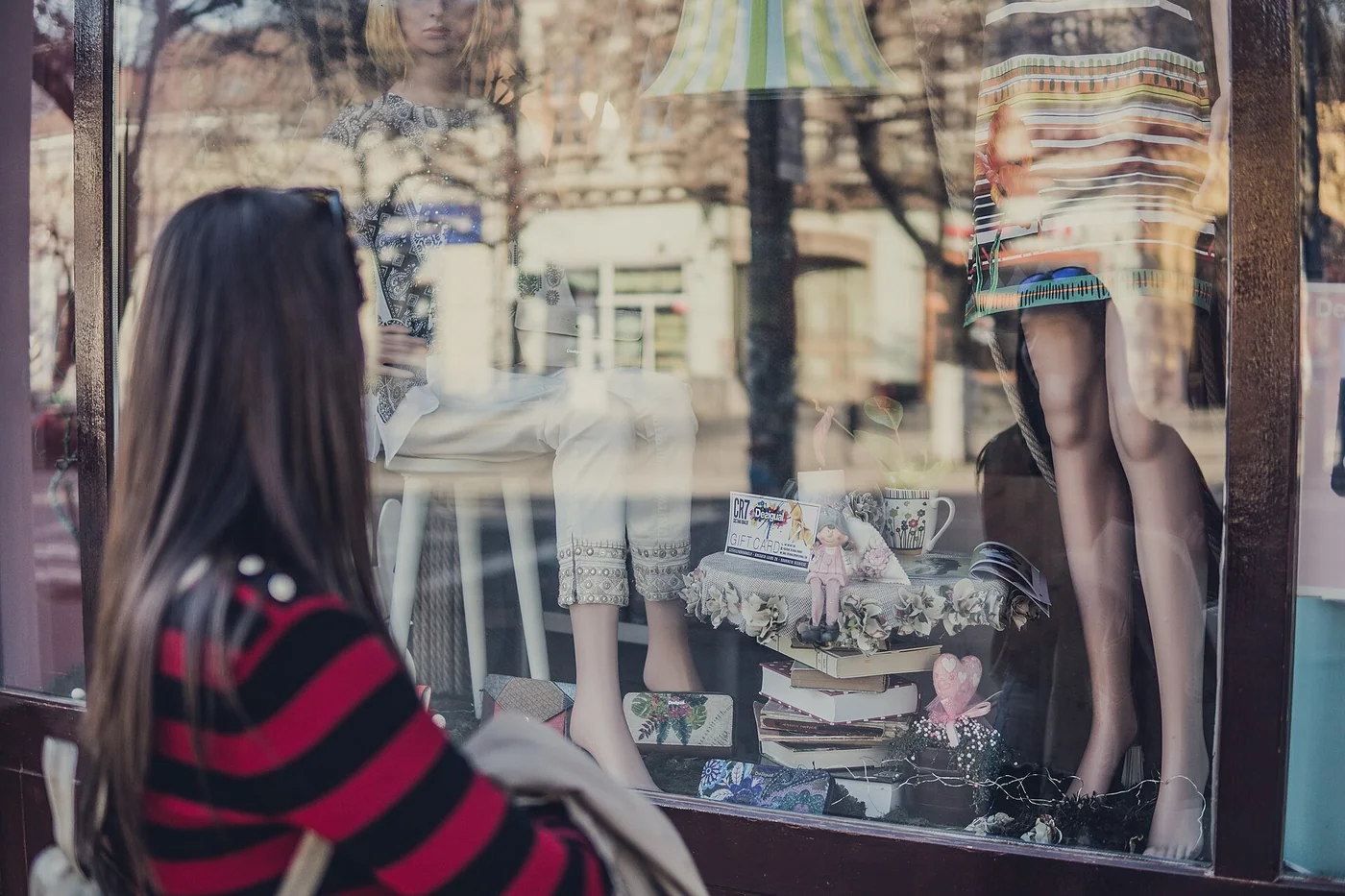 Une passante regarde une vitrine de boutique