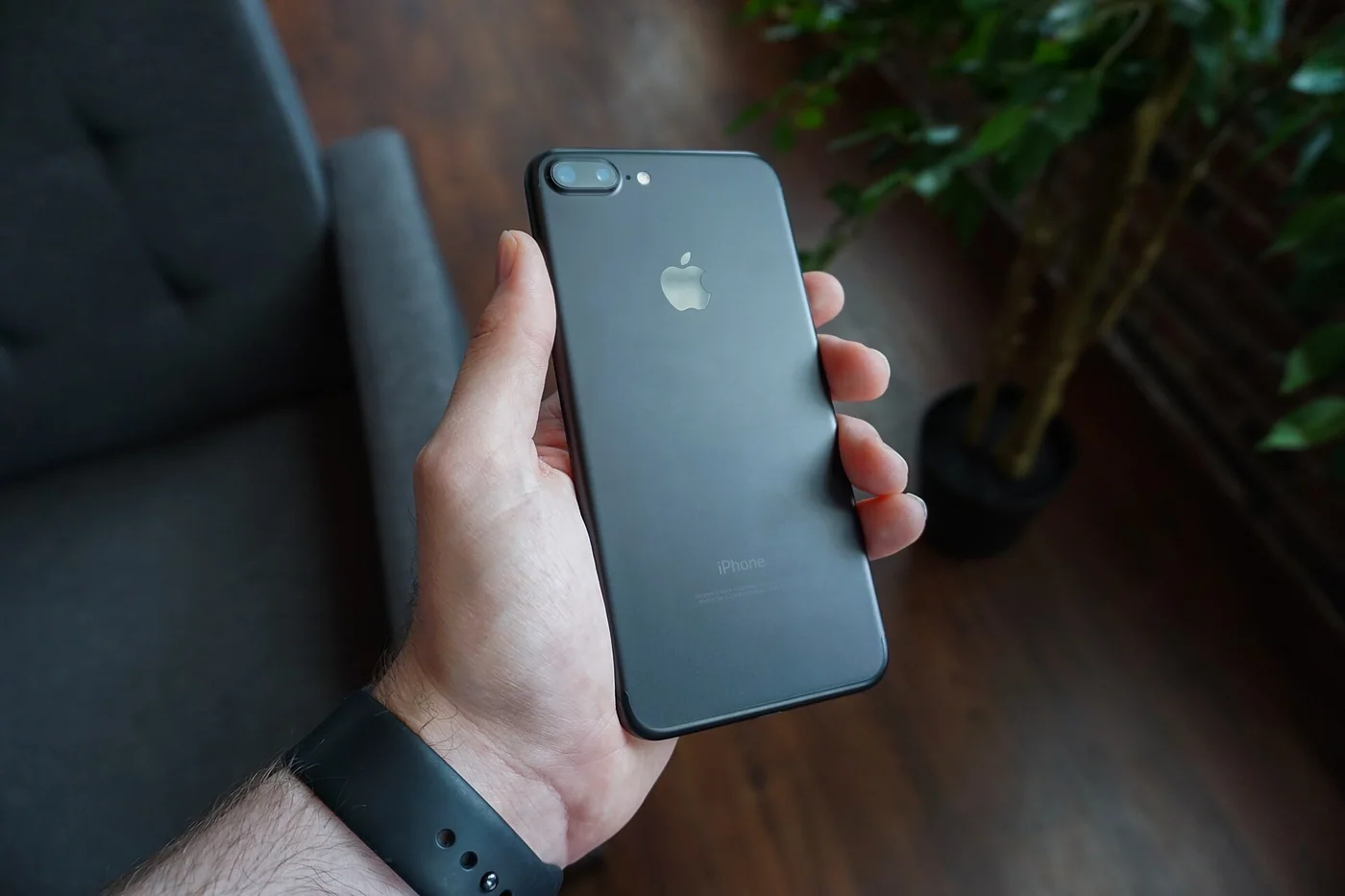 Un téléphone noir tenu dans une main, vu de dos