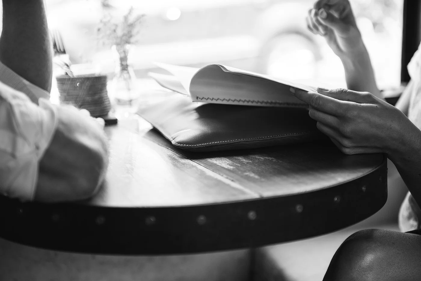 Des personnes autour d’une table de café, dont une tient un journal ouvert